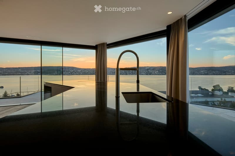 Modern, minimalist bathroom with large windows offering a scenic view of the water and cityscape. Features a sleek, contemporary faucet and sink.