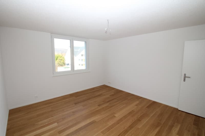 Empty room with white walls, wooden floor, and a window with white frame. No furniture or equipment present.