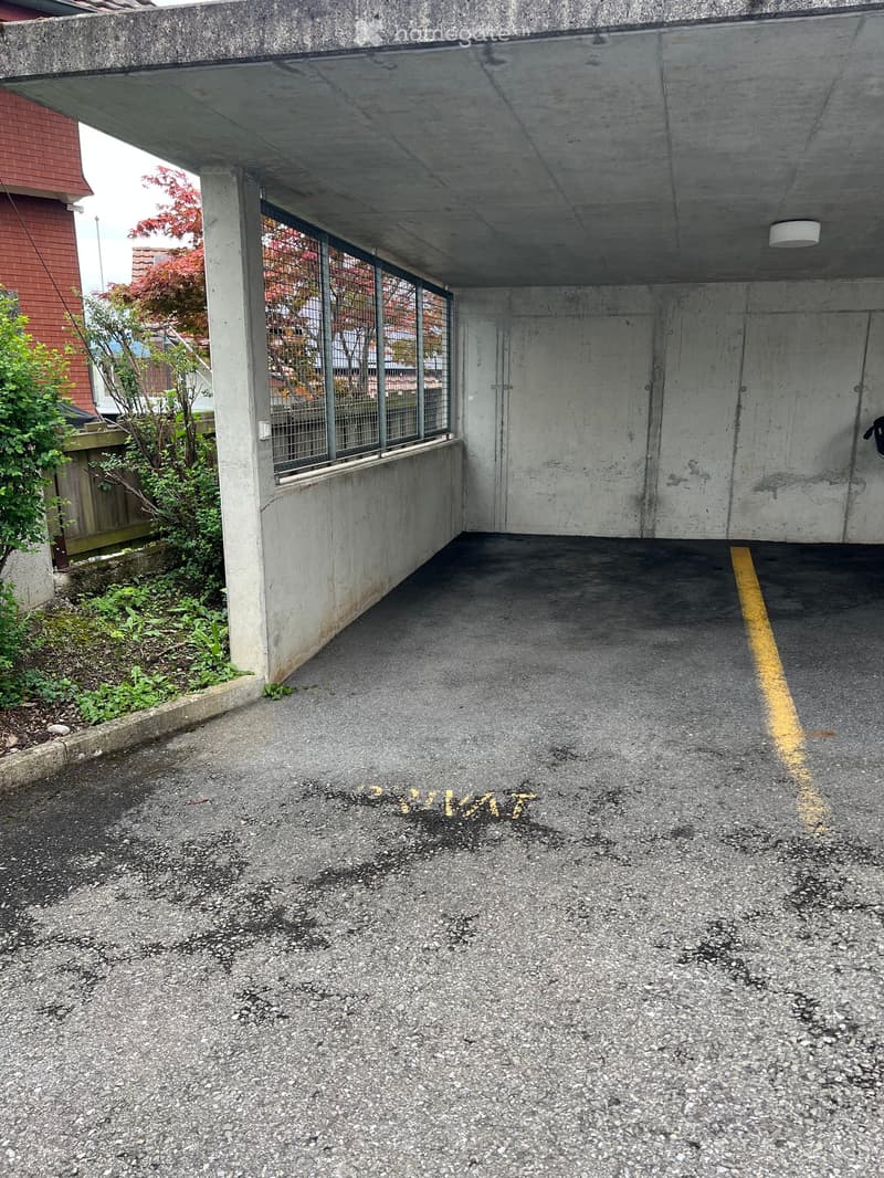 Underground garage with concrete walls, a single parking space, and a small window with metal bars.