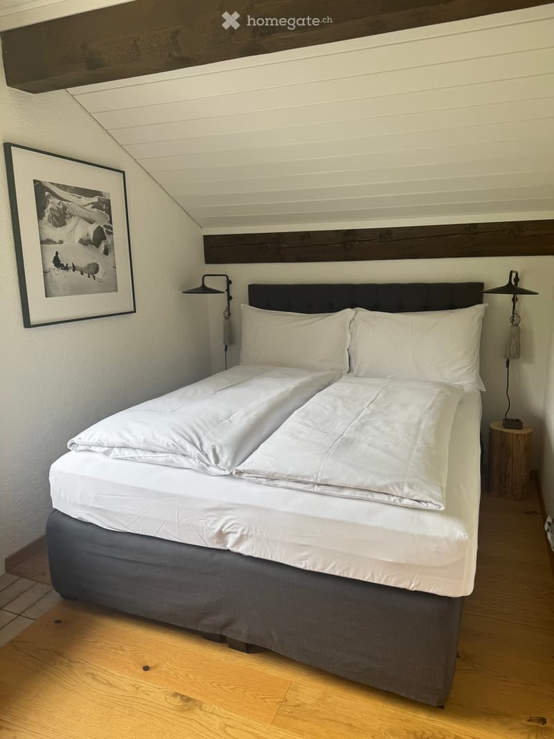 A cozy bedroom with a neatly made double bed, white bedding, wooden nightstands, and a framed picture on the wall.