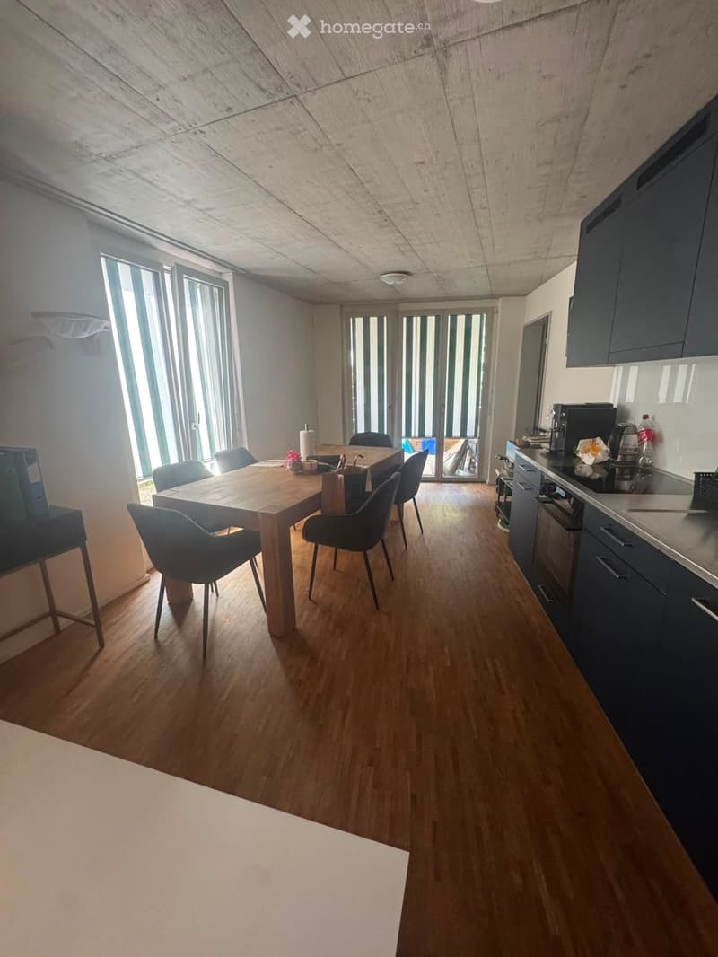Open-plan kitchen and dining area with wooden flooring, modern cabinets, and a dining table with chairs.