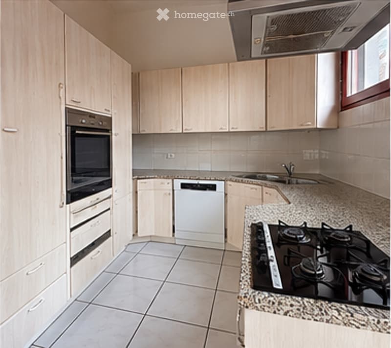 Modern kitchen with light wood cabinets, stainless steel appliances, granite countertops, and tiled flooring.