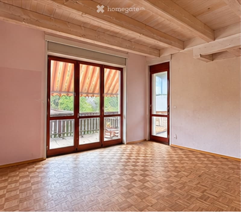 Empty room with wooden flooring, light pink walls, and large sliding glass doors leading to a balcony.