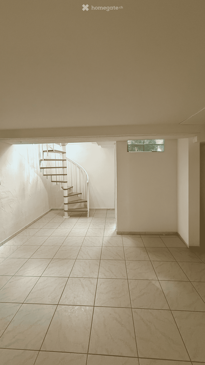 Empty hallway with tiled floor, beige walls, and a spiral staircase leading upwards.