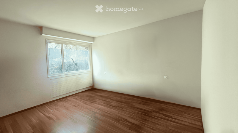 Empty room with wooden flooring, white walls, and a single window with blinds.