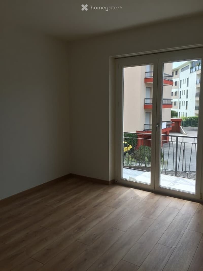 Empty room with wooden flooring and large sliding glass doors leading to a balcony.