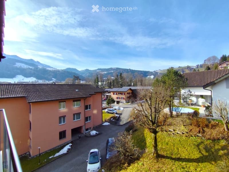 A building with a car parked in front, a swimming pool, and a mountain in the background.