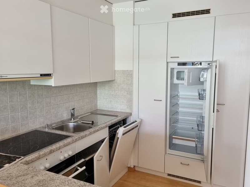 Modern kitchen with white cabinets, granite countertop, stainless steel sink, oven, dishwasher, and refrigerator.