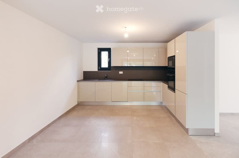 Empty kitchen with light-colored cabinets, a dark countertop, and a tiled floor. No appliances or furniture are present.
