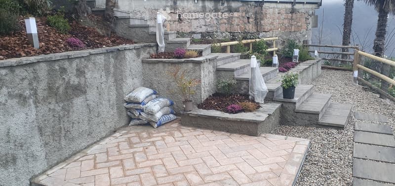 Garden / Outdoor Area. Outdoor garden area with stone steps, potted plants, gravel, and stacked bags of material.