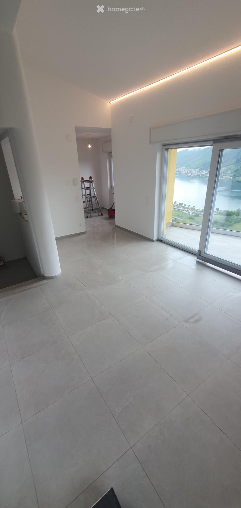 Unfurnished Room. Empty room with large windows, tiled floor, and white walls. A ladder and cleaning supplies are visible in the background.