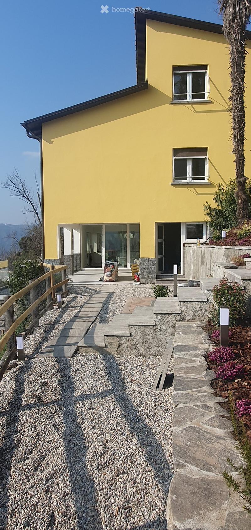House. Two-story yellow house with white-framed windows, stone steps, and a gravel pathway leading to the entrance.