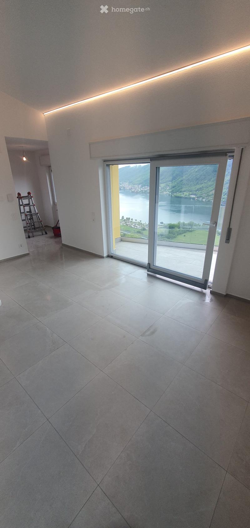 Unfurnished Room. Empty room with large sliding glass door leading to a balcony with scenic lake view, tiled floor, and modern lighting.