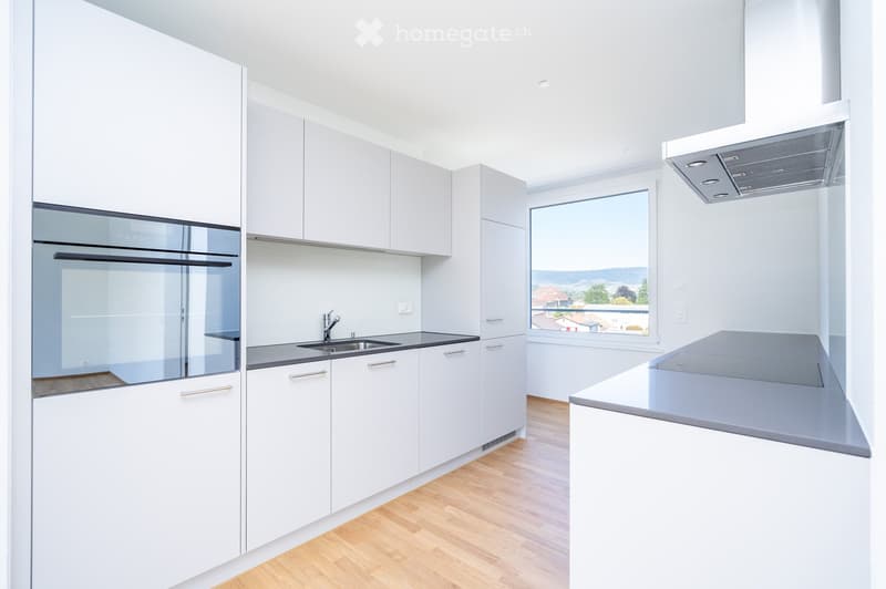 Modern kitchen with white cabinets, stainless steel sink, and a large window offering a scenic view.