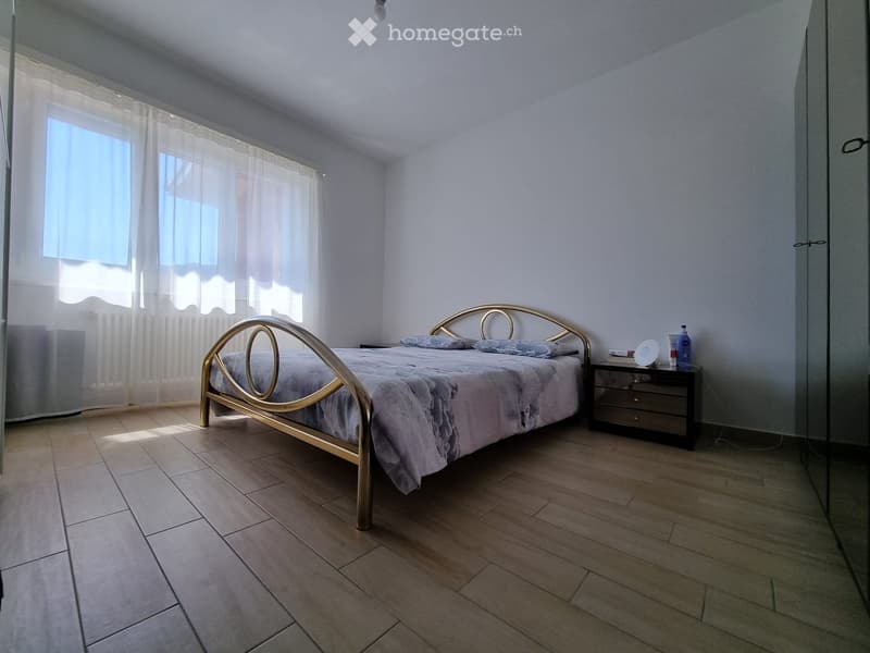 Bedroom with a bed, nightstand, and a window with curtains