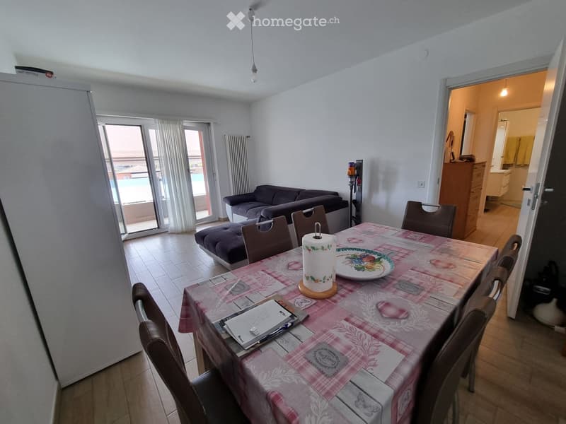 Dining room with a table, chairs, and a couch near a balcony with a view