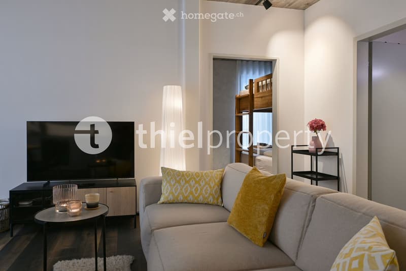 gray couch, wooden side table, yellow pillows, flat screen tv, lamp, wooden bunk bed, flower vase