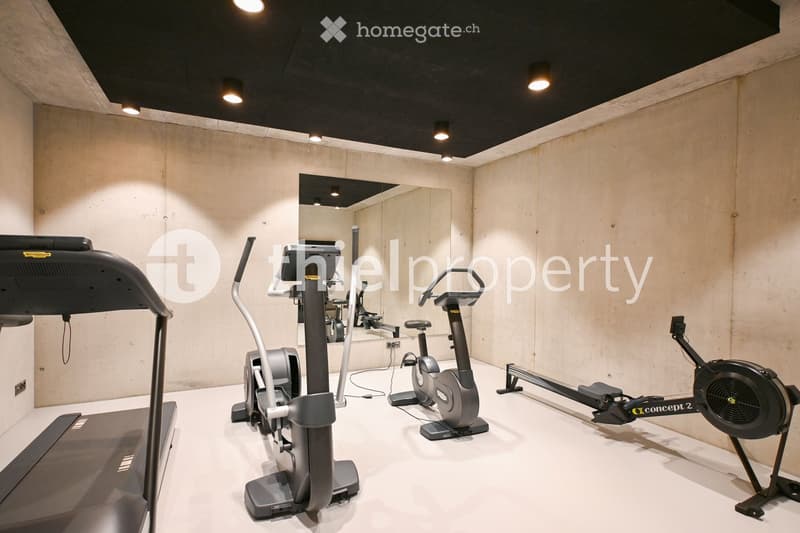 Modern home gym with treadmill, elliptical machine, exercise bike, and rowing machine.