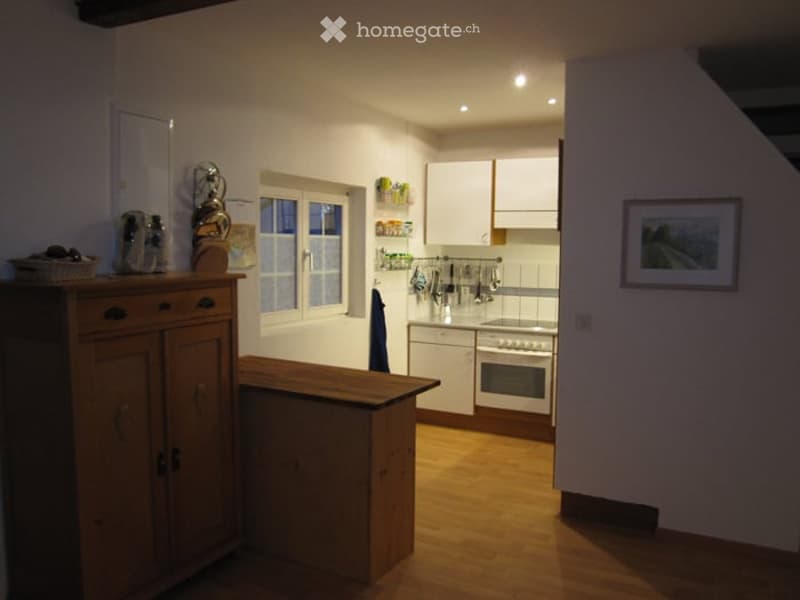 Bright kitchen with white cabinets, wooden floor, central island, and various appliances including an oven and sink.