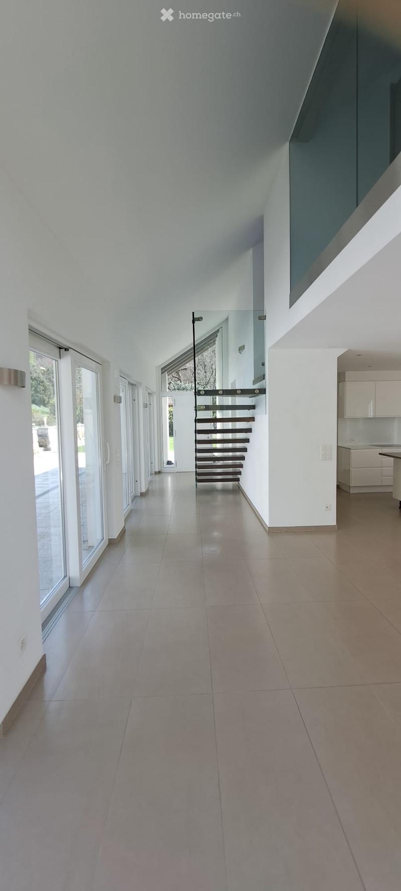 Modern hallway with large glass doors, tiled floor, and a staircase leading upwards.