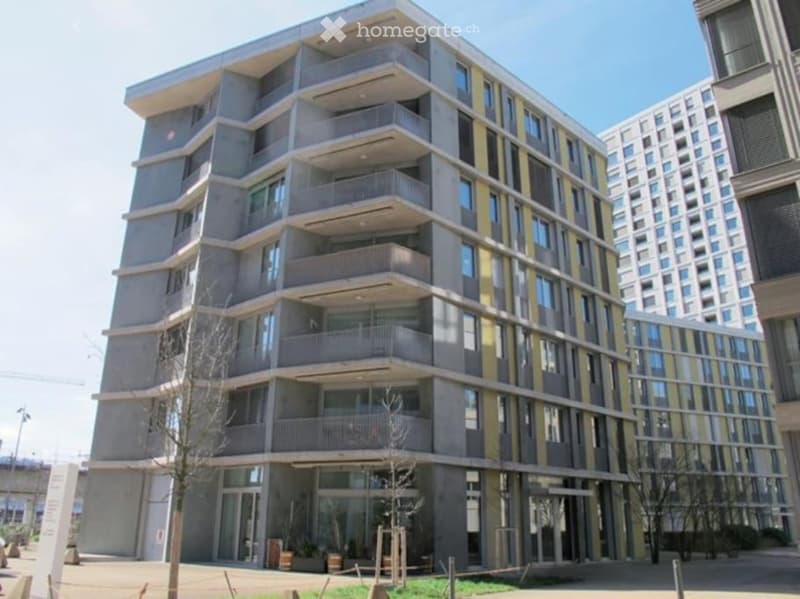 Modern multi-story apartment building with balconies, large windows, and contemporary design.