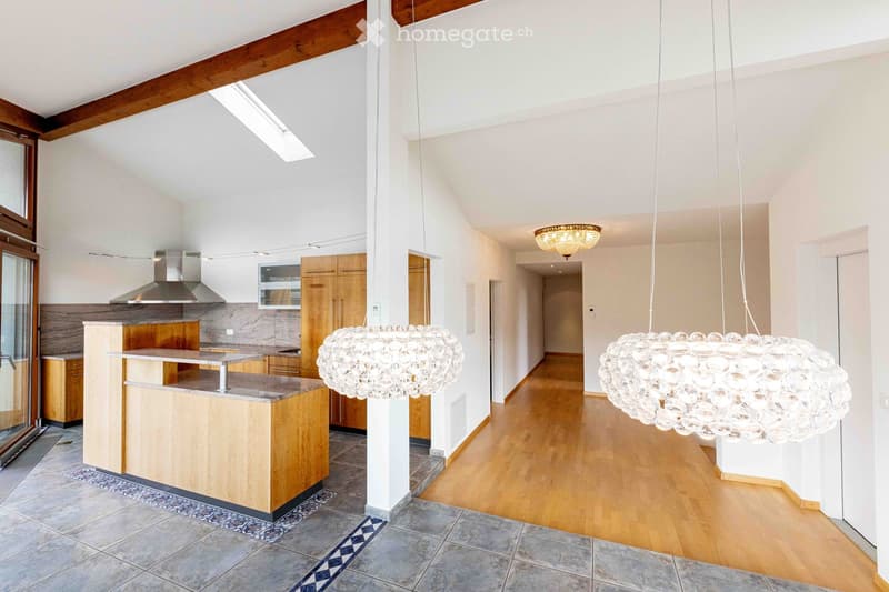 Modern kitchen with wooden cabinets, stainless steel range hood, central island, and large pendant lights.