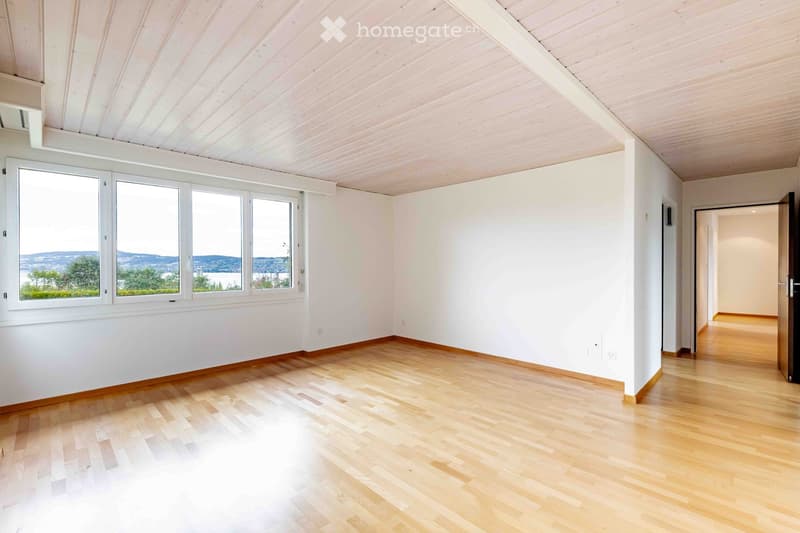Empty room with light wooden flooring, white walls, and large windows offering a scenic view. No furniture or equipment present.