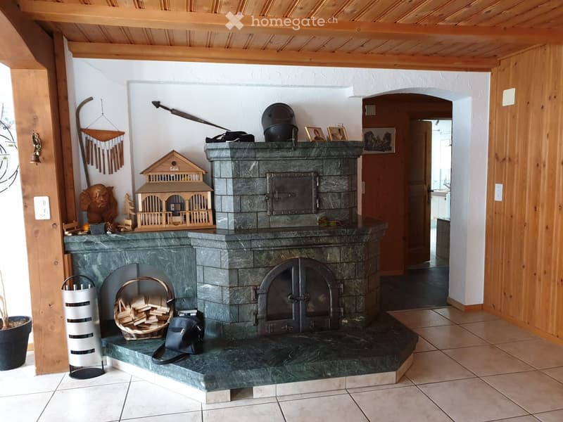 Hallway with a stone fireplace, decorative items, and a doorway leading to another room.