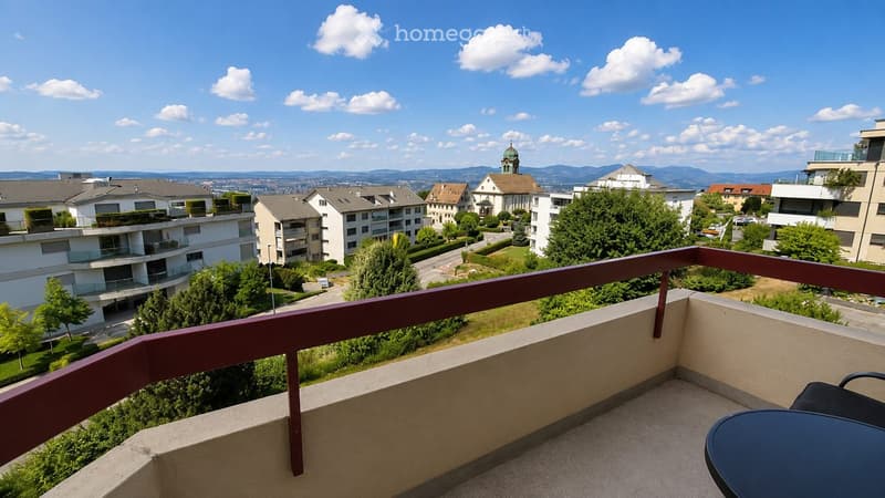 Balcony with a view of a residential area, featuring a table and a chair.