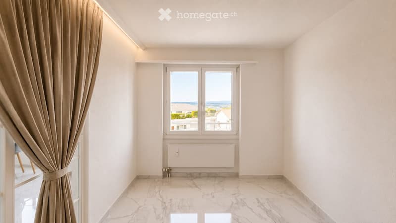Empty room with marble flooring, white walls, large window with view, and beige curtains.