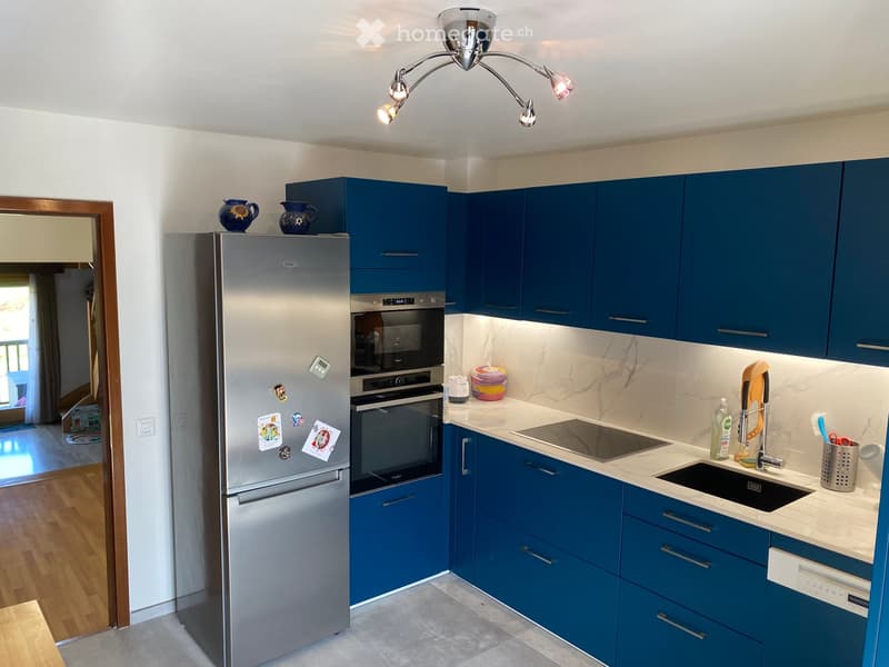 Modern kitchen with blue cabinets, stainless steel appliances, marble countertops, and a sleek design.