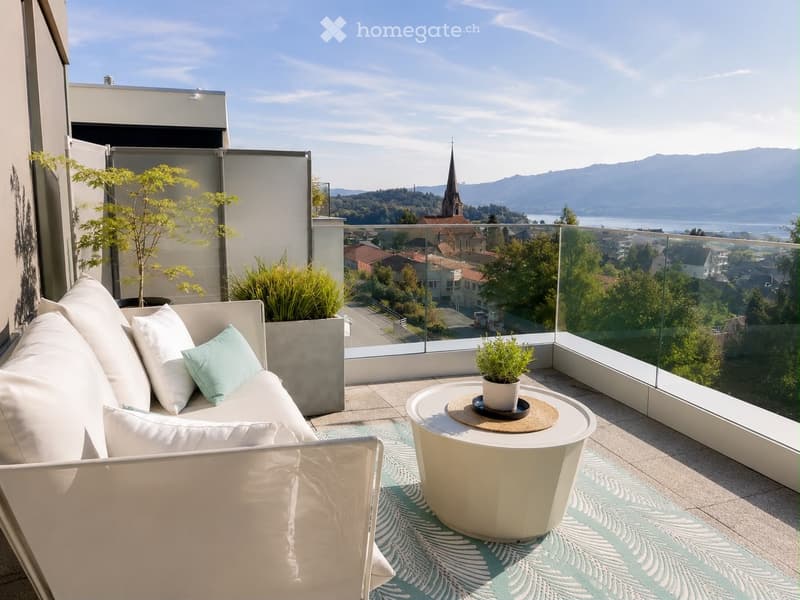 Modern balcony with white sofa, round table, potted plants, and scenic city view.