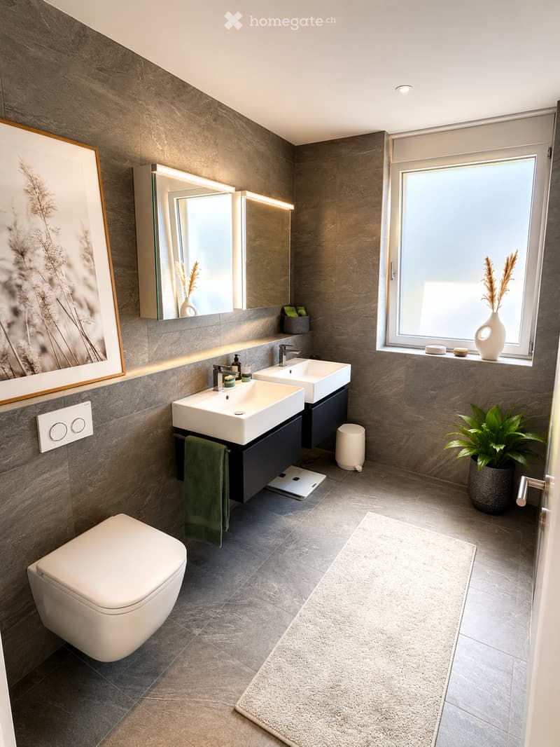 Modern bathroom with dark grey tiles, white toilet, double sink vanity, large mirror, and a window with a plant on the sill.