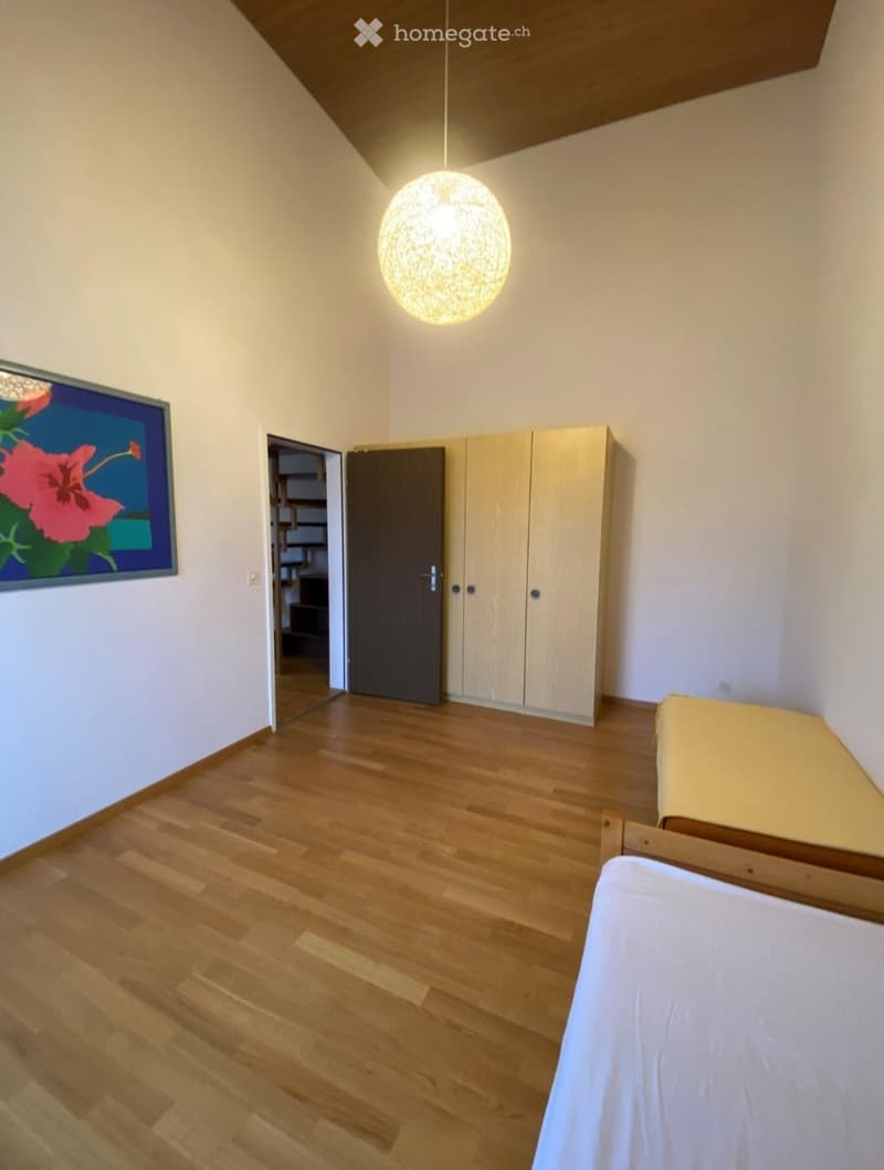 Bright bedroom with wooden flooring, a single bed, a wardrobe, and a decorative picture frame on the wall.
