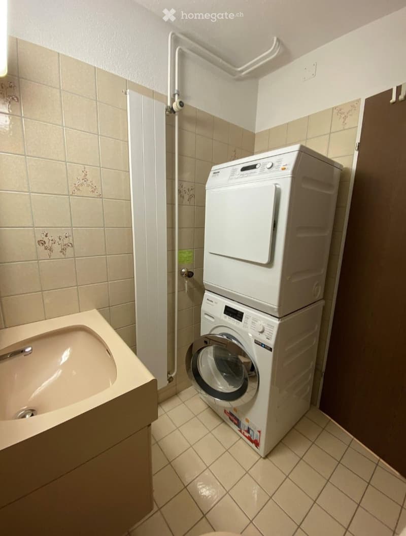 Bathroom with a bathtub and a stacked washing machine and dryer unit.