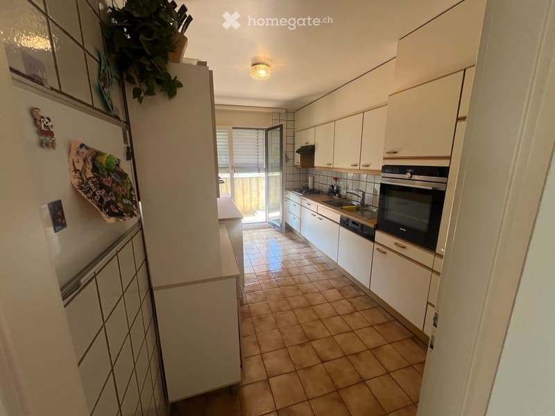 Modern kitchen with white cabinets, tiled floor, and stainless steel appliances including a refrigerator, oven, and sink.