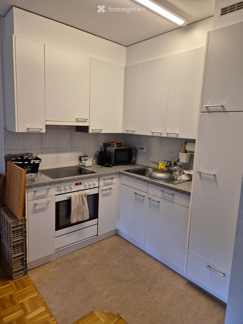 Modern kitchen with white cabinets, granite countertops, stainless steel sink, oven, microwave, and various small appliances.