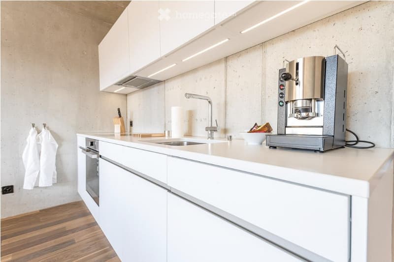 Modern kitchen with white cabinets, a coffee maker, a sink, an oven, and a knife block on the counter.