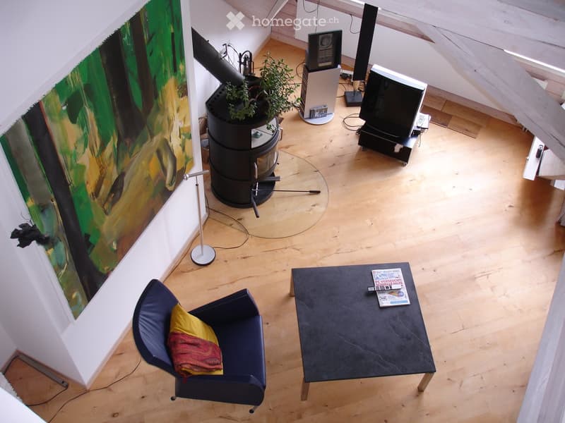 Modern living room with wooden floor, large painting, sofa, coffee table, TV, speakers, and a plant in a pot.