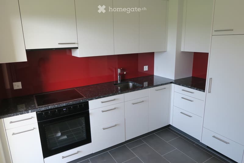 Modern kitchen with white cabinets, dark granite countertops, stainless steel sink, electric stovetop, and built-in oven.