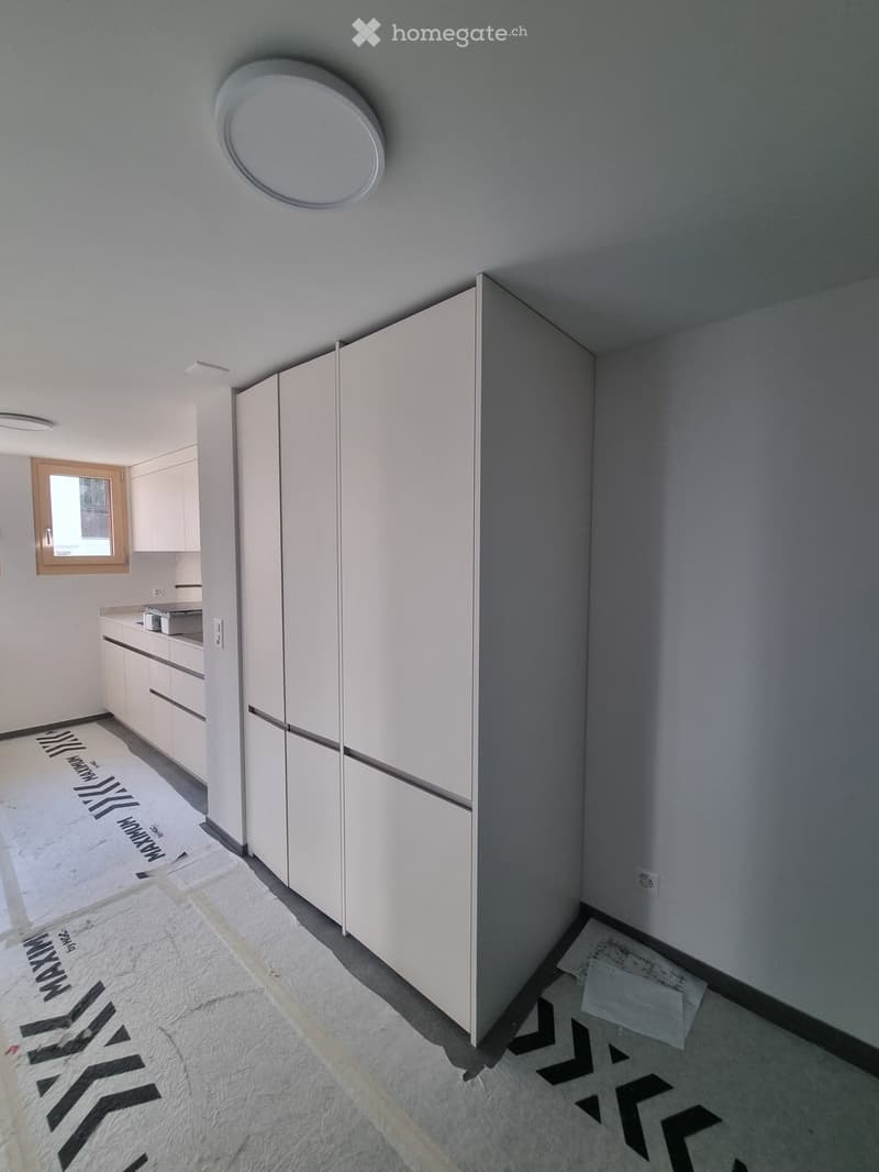 Empty room with white cabinets, a small window, and a white floor. No furniture or equipment present.