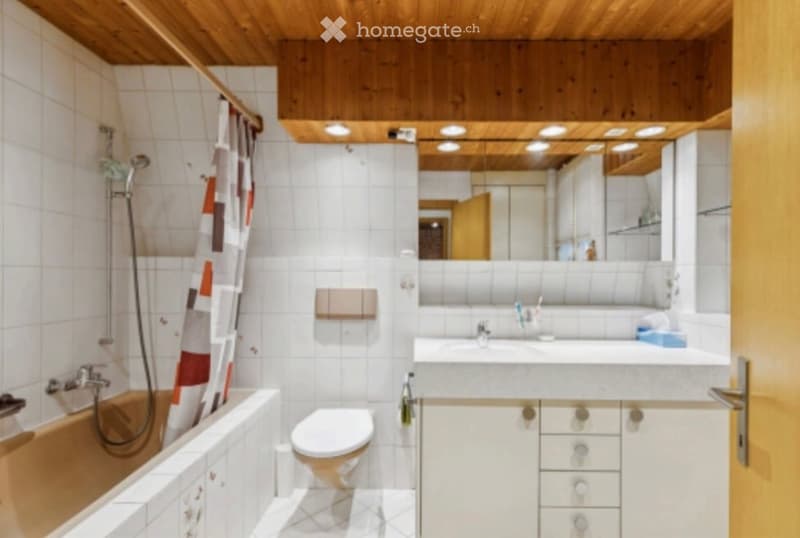 Bathroom with white tiles, wooden ceiling, bathtub, toilet, sink, mirror, and shower curtain.