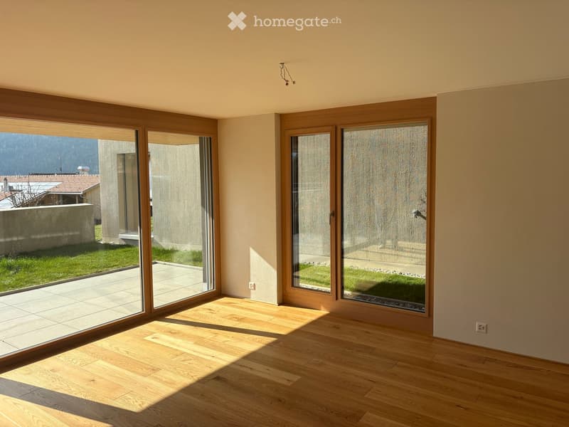Empty room with wooden flooring, large sliding glass doors, and natural light. No furniture or equipment present.