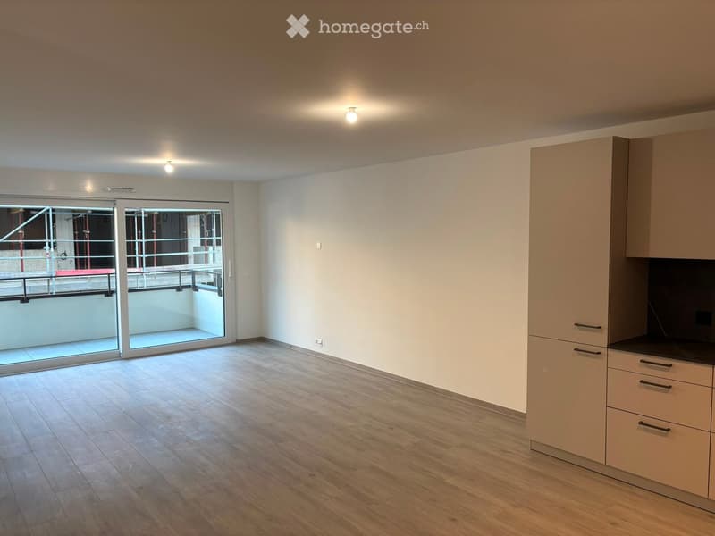 Empty room with wooden flooring, white walls, and a sliding glass door leading to a balcony area.