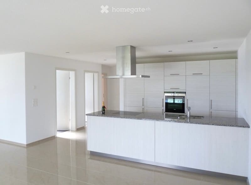 Modern kitchen with white cabinets, stainless steel appliances, granite countertop, and a bottle on the counter.