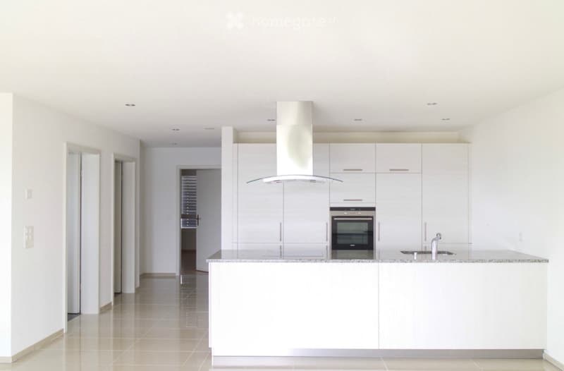Modern, minimalist kitchen with white cabinets, stainless steel appliances, and a central island.