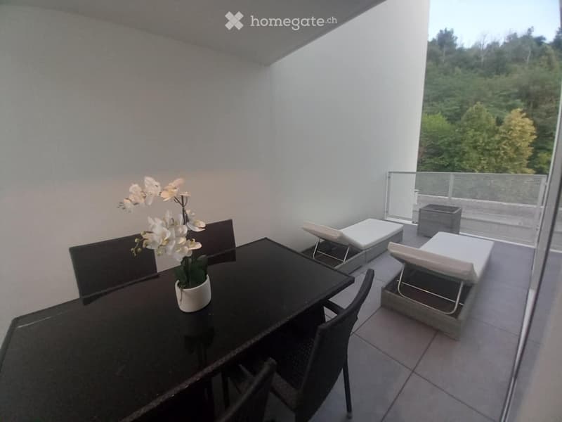 Balcony with a black dining table, chairs, lounge chairs, and a flower pot with white orchids.