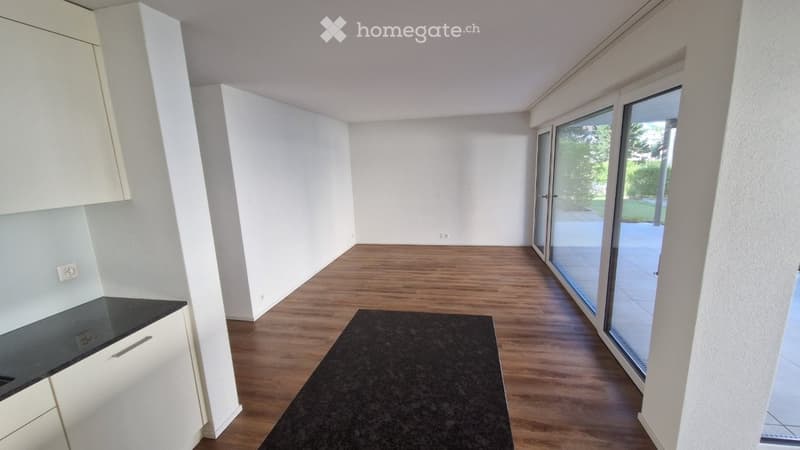 Empty room with wooden flooring, white walls, and large sliding glass doors leading to an outdoor area.
