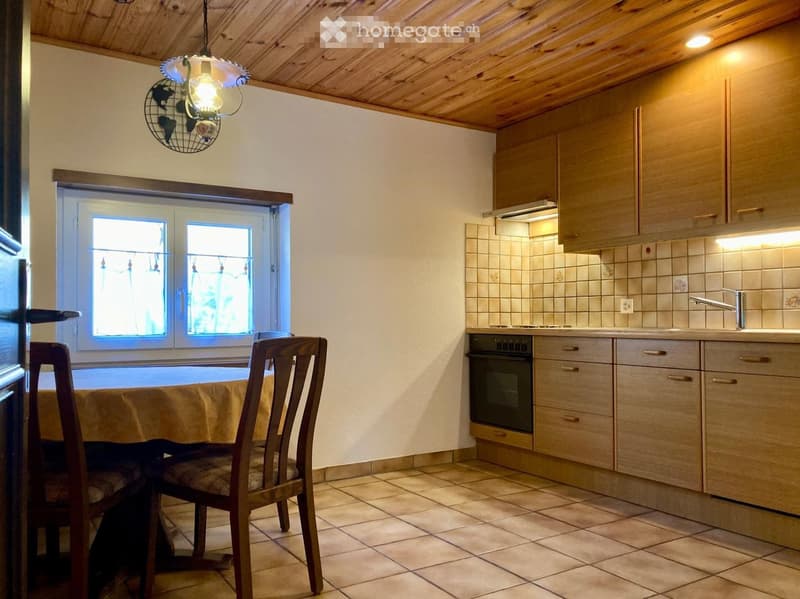 Cozy kitchen with wooden cabinets, tiled backsplash, and a dining area featuring a table and chairs.
