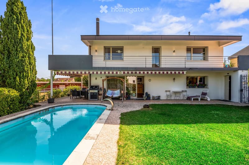 Modern two-story house with a swimming pool, outdoor seating area, and well-maintained garden.